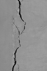 Crack in a gray painted plaster wall of a house. Cracked cement wall - obrazy, fototapety, plakaty