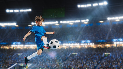 Aesthetic Shot Of Athletic Child Soccer Football Player Jumping And Kicking Ball Mid-Air On Stadium WIth Crowd Cheering. Young Boy Scoring a Goal on Junior World Championship Tournament Match.