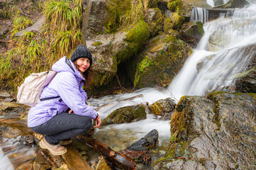 Woman hiker contemplating a waterfall on a sunny day - 785357529