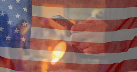 Image of American flag waving over man using phone in the background