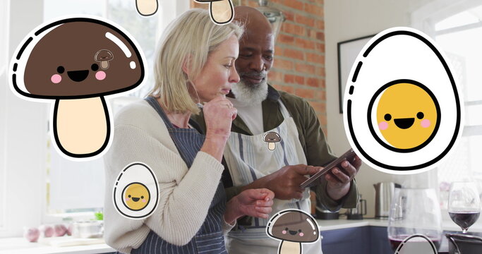 Image of food icons over diverse couple using tablet in kitchen - Powered by Adobe