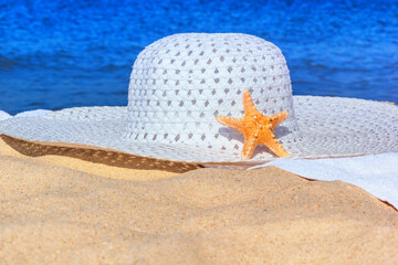 Close-up view of a sun hat on a sandy beach by the sea, selective focus. Beach holiday concept, background with copy space for text