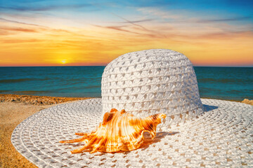 Close-up view of a sun hat on a sandy beach by the sea at sunset, selective focus. Beach holiday concept, background with copy space for text