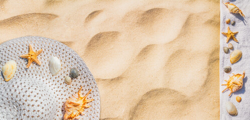 Top view of a beach hat with seashells on the sand under the hot summer sun, horizontal banner. Concept of sandy beach holiday, flat lay, background with copy space for text