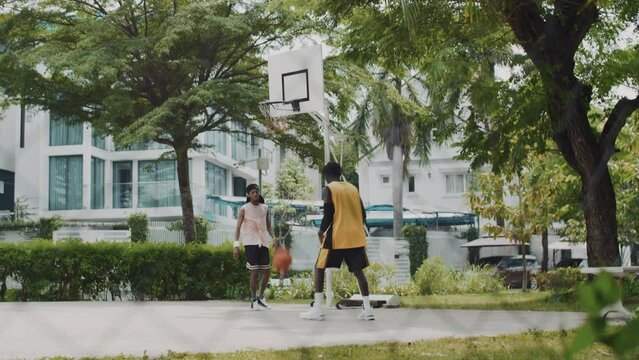 Extreme long shot of basketball players throwing ball in ring while spending time on outdoor court