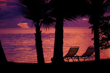 A view of two long chairs in silhouette on a small beach of the Rangiroa Atoll. Tuamotu Archipelago, French Polynesia, November 11, 2022