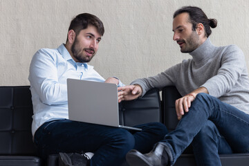 deux collègues et amis travaillent et discutent , assis sur un sofa dans les bureaux de leur entreprise. 