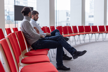 deux hommes discutent dans une salle de conférence ou une salle de réunion, assis sur une rangée...