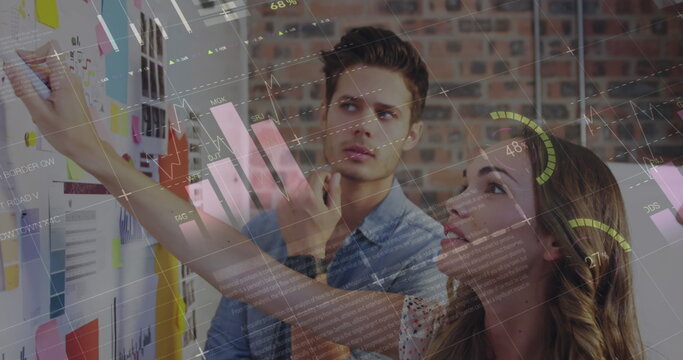 Statistical data processing against diverse male and female colleagues discussing over whiteboard