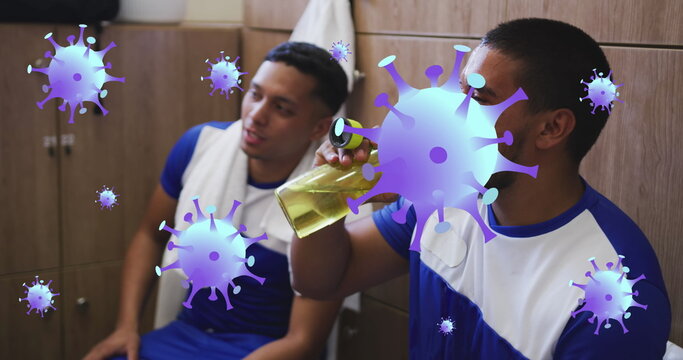 Image of covid-19 cells icons over hispanic male soccer player putting water on his face