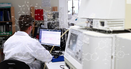 Image of chemical formulas over back view of caucasian male lab worker using computer - Powered by Adobe