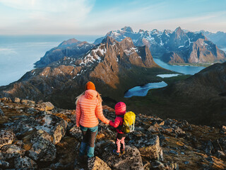Family hiking travel in Norway - mother and child on mountain summit in Lofoten islands adventure healthy lifestyle outdoor, parent and kid climbing together active vacations with backpack - 785381777