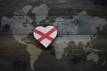 wooden heart with national flag of alabama state near world map on the wooden background.