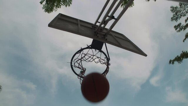 Directly below view of streetball ring with net and basketball ball on sky background with nobody around