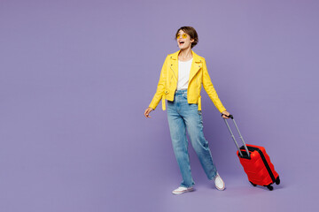 Traveler fun woman wear yellow casual clothes hold suitcase bag look aside isolated on plain purple...