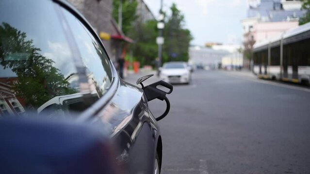 a cable at a city charging station charges an electric car in close-up. i. Plug-in module. the traffic is blurry