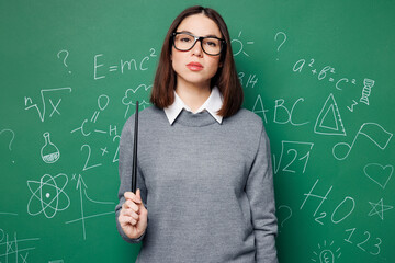 Young strict serious smart teacher woman wears grey casual shirt glasses hold pointer look camera...