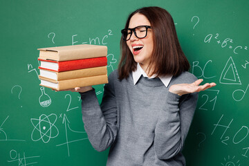 Young dissatisfied sad smart teacher woman wears grey casual shirt glasses hold in hand book look...