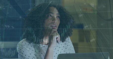 Image of graphs and escalator over thoughtful biracial woman writing notes on laptop