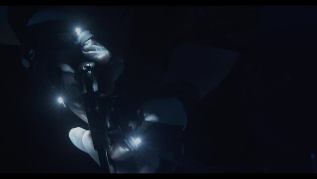 detail shot of a man grabbing a gun in the dark with gloves