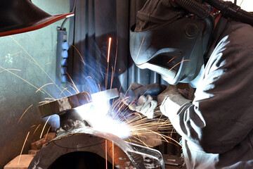 Welder in protective clothing at the workplace in an industrial company in steel construction - 785398199