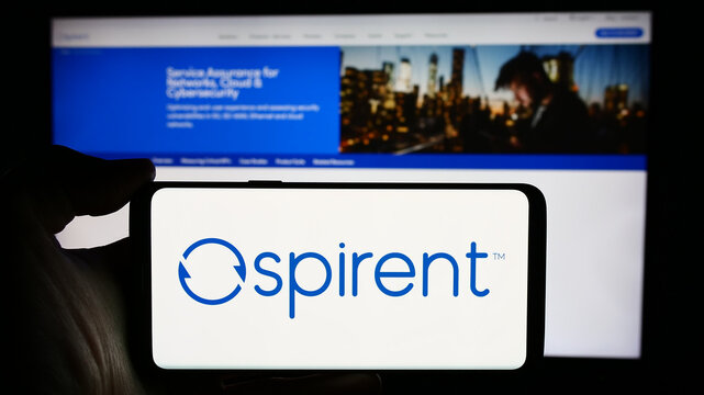 Stuttgart, Germany - 04-08-2024: Person holding cellphone with logo of British company Spirent Communications plc in front of business webpage. Focus on phone display.