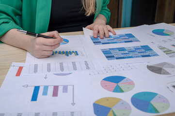 Kobieta pracuje w finansach, siedzi przy biurku nad wykresami I tabelami z liczbami
