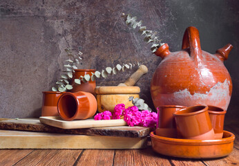 Bodegón con un viejo botijo, utensilios de madera y cerámica y flores de kalanchoe y ramas de...