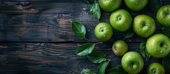A group of fresh green apples with leaves on top of a rustic wooden table.