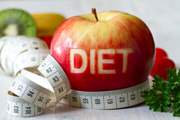 Red apple with cut-out word diet, measuring tape and fruits, diet and healthy lifestyle concept