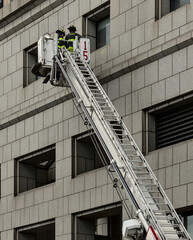 firefighters on a ladder against a building (unrecognizable, no face) FDNY new york fire fighters department on fire engine (emergency response agency) fireman