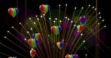 Image of pride rainbow hearts and fireworks exploding on black background