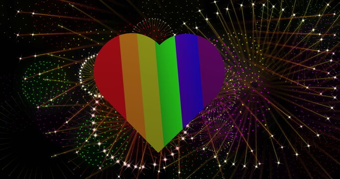 Image of pride rainbow heart and fireworks exploding on black background