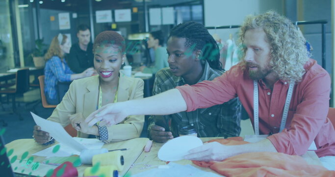 Image of graphs moving over diverse designers choosing from colour swatch at desk - Powered by Adobe