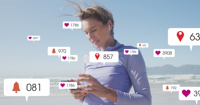 Image of social media data processing over caucasian woman with smartphone on beach - Powered by Adobe