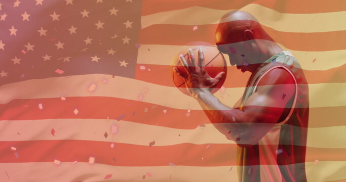 Image of american flag over focused african american male basketball player holding ball - Powered by Adobe