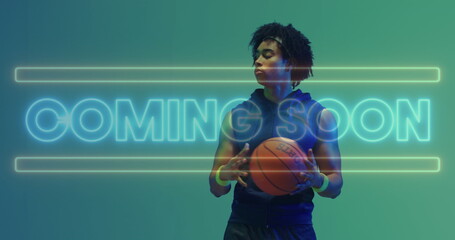 Image of coming soon text in neon over african american male basketball player holding ball