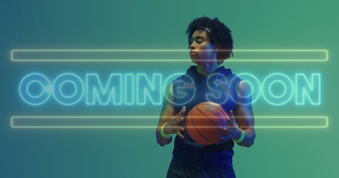 Image of coming soon text in neon over african american male basketball player holding ball
