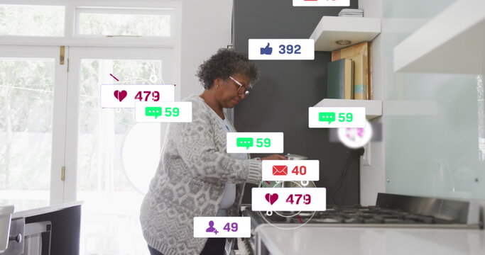 Image of social media text and icons over senior african american woman at home