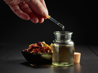 Dropping essential oil or herbal tincture into a small bottle.