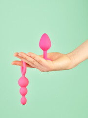 Woman's hand holding adult sex toy over mint background - 785414515