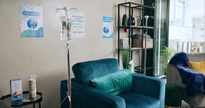 Clinic interior, iv drip and equipment for healthcare, services and medicine by sofa in patient lounge. Furniture, pharmaceutical and liquid in bag for wellness with medical tools by couch in room