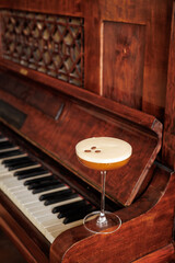 a glass of alcoholic coffee cocktail standing on an open piano. An atmosphere of rest and relaxation. The keys of an antique piano create a beautiful backdrop. Coffee lovers. Vintage party.