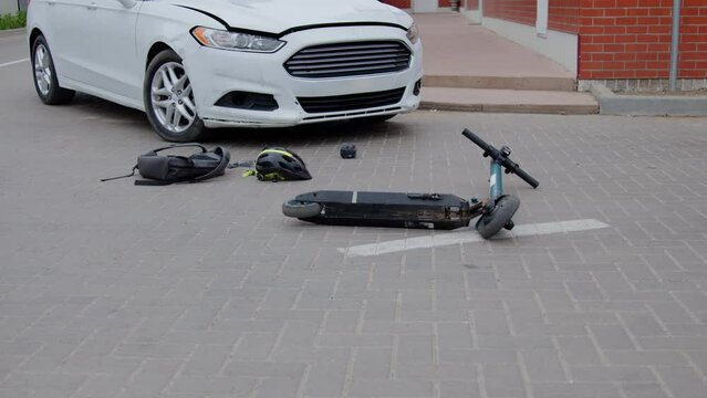 Discarded scooter lies inert on road surface after car accident. Scene illustrates aftermath of dangerous accident emphasizing potential risks associated with such roadway collisions.