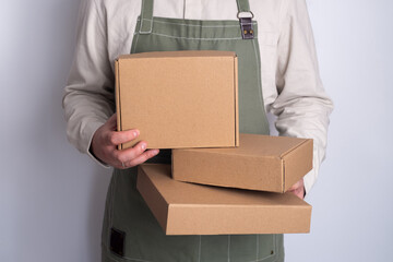 Man holds a paper box in his hand. Person with new package. Postal services, delivery. Kraft paper. Gift box, gift. Box close-up. Empty packaging, empty space. Communication of people. Cardboard case