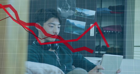 Image of multiple falling graphs over asian boy playing game on digital tablet - Powered by Adobe