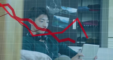 Rolgordijnen Aziatische plekken Image of multiple falling graphs over asian boy playing game on digital tablet