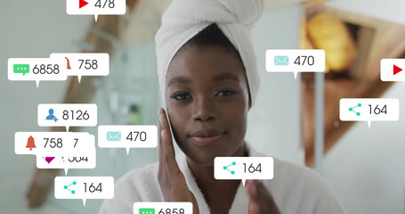 Image of notification bars, african american woman gently massaging face while looking in mirror