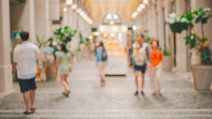 A blurry image of a busy city street with people walking and shopping