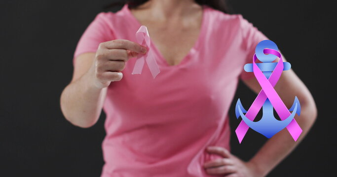 Ribbon over a anchor icon over mid section of woman holding a pink ribbon against black background